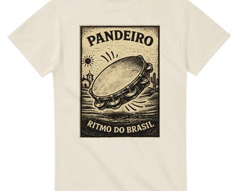 May include: Cream-colored t-shirt featuring a black and white illustration of a tambourine with the text "Pandeiro" and "Ritmo do Brasil". The design includes a sun, a church, and cacti, evoking a Brazilian theme.
