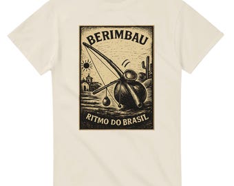 May include: Cream-colored t-shirt featuring a black and sepia illustration of a berimbau, a Brazilian musical bow, with the text "BERIMBAU" and "RITMO DO BRASIL". The design includes a sun, church, and cactus.