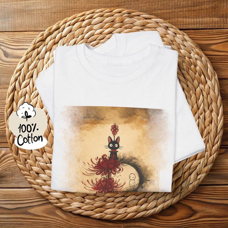May include: White t-shirt with a graphic of a black cat, red flowers, and a small white figure. The shirt is made of 100% cotton. The text on the shirt says 100% Cotton.