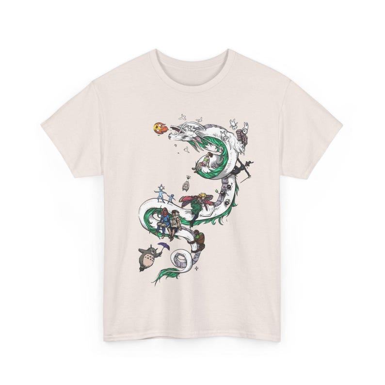 May include: Cream-colored t-shirt featuring a detailed illustration of a white and green dragon with various animated characters. The design includes a variety of colors and intricate details, creating a whimsical and artistic aesthetic.