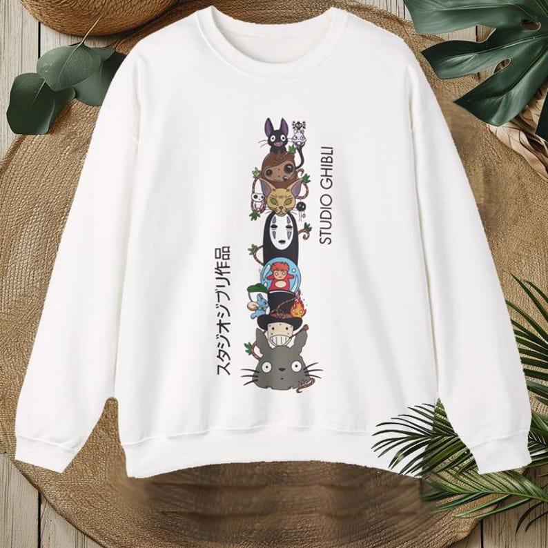 Puede incluir: Sudadera blanca con un dise&ntilde;o apilado de personajes de Studio Ghibli, incluyendo a Totoro y Sin Cara. El dise&ntilde;o incluye texto japon&eacute;s y las palabras "STUDIO GHIBLI" en negro. La sudadera tiene mangas largas y cuello redondo.