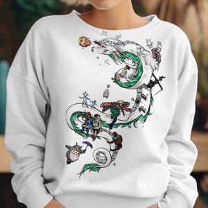 May include: White sweatshirt featuring a detailed illustration of a white dragon with green accents, and various cartoon characters. The design includes a variety of characters and elements, creating a whimsical and artistic aesthetic.