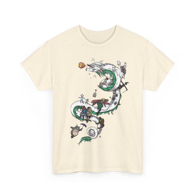 May include: Cream-colored t-shirt featuring a detailed illustration of a white and green dragon with various animated characters. The dragon winds across the shirt, with characters riding and interacting with it. The design is intricate and colorful.