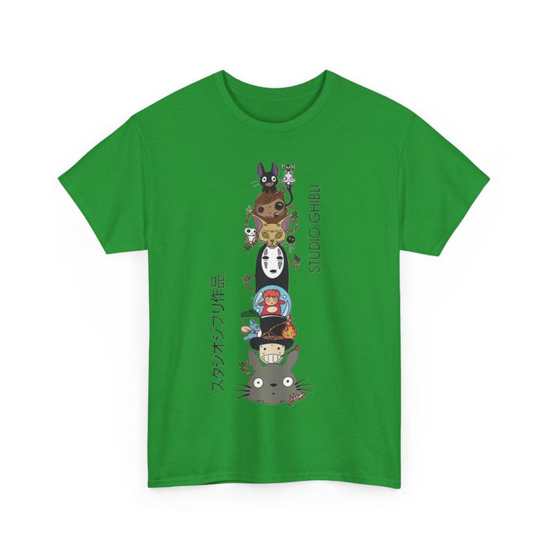 Puede incluir: Camiseta verde con un dise&ntilde;o vertical de personajes de dibujos animados de Studio Ghibli, incluyendo a Totoro y Sin Cara. La camiseta tambi&eacute;n presenta el texto "STUDIO GHIBLI" y texto japon&eacute;s. Un dise&ntilde;o vibrante y colorido.