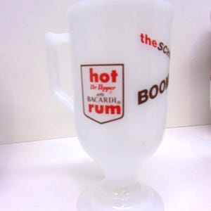 May include: White glass mug with a handle and a flared base. The mug features red and brown text that reads "hot Dr Pepper and BACARDI RUM" and "the SCH BOOM".