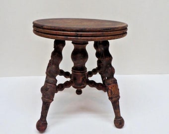 May include: A small, antique wooden stool with a round top and three ornate legs. The stool is made of dark brown wood and has a classic, vintage design. The legs have a decorative, turned design, and the stool is likely around 18 inches tall.
