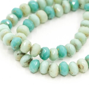Pu&ograve; includere: Una collana di perline di vetro verde chiaro e turchese. Le perline sono sfaccettate e hanno una forma leggermente irregolare.