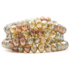 May include: A close-up of a stack of brown and green faceted glass beads. The beads are arranged in a circular pattern, creating a decorative and eye-catching display.