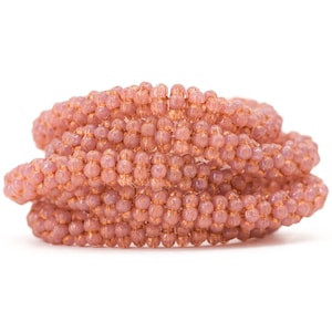 May include: A close-up of a pink beaded bracelet, made of small, round beads, twisted into a spiral shape.