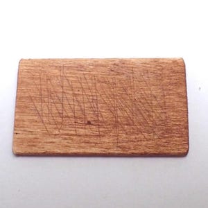 May include: A small, rectangular wooden cutting board with visible knife marks. The board is a warm brown color and appears to be well-used. The cutting board is likely used for food preparation.