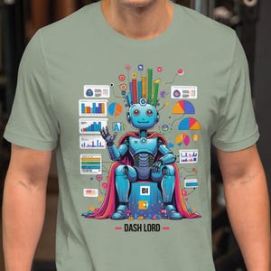 Puede incluir: Camiseta verde salvia con un diseño de robot de dibujos animados. El robot azul lleva una capa roja y está sentado en un trono. El texto "DASH LORD" está debajo. El diseño incluye gráficos de datos coloridos.