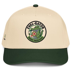 May include: A cream-colored baseball cap with a dark green brim and a circular embroidered patch on the front. The patch features a green alligator holding a clipboard and a magnifying glass, with the text EVAL-GATOR and TRUST, THEN TEST.