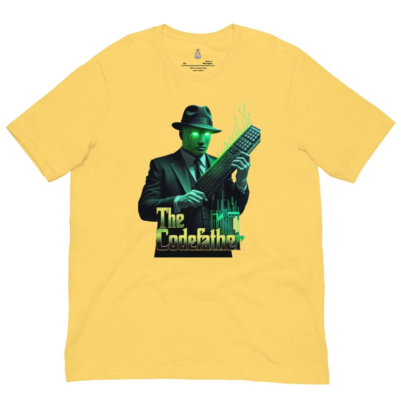 May include: A yellow short-sleeve t-shirt featuring a graphic of a figure in a suit and fedora with a digital green face holding a computer keyboard. The text below the figure reads The Codefather in a stylized font with green circuit accents.