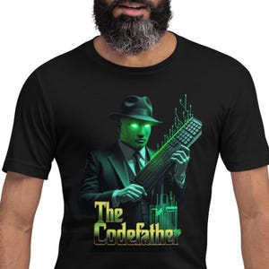 Peut inclure: T-shirt noir avec un motif d'art numérique. Le graphisme représente une figure en costume et fedora avec un visage numérique vert et des yeux brillants, tenant un clavier. Le texte "The Codefather" est en vert et or.