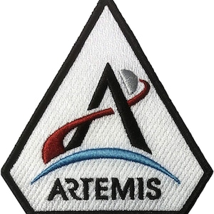 Peut inclure: Un écusson brodé triangulaire à fond blanc avec une bordure noire. Il présente une grande lettre A noire, un arc rouge, une ligne courbe bleue représentant un horizon, une petite lune argentée et le mot ARTEMIS en lettres noires.