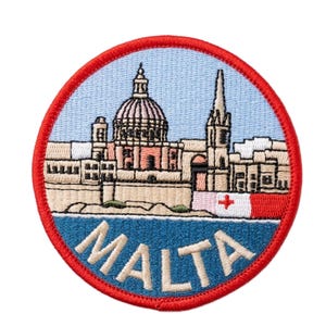 May include: Embroidered patch featuring a cityscape with a domed building and a tall spire, set against a light blue sky and dark blue water. The word "MALTA" is embroidered in white. The patch has a red border and a Maltese flag.