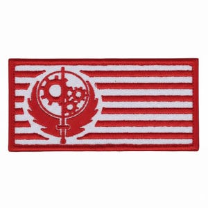 May include: A rectangular embroidered patch featuring a red and white striped background. Centered on the left side is a red emblem depicting a vertical sword intersecting a circular gear mechanism, all framed by a thick red stitched border.