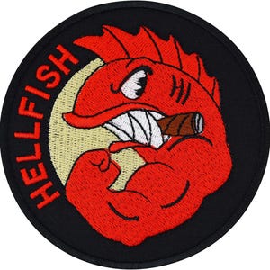May include: A circular embroidered patch with a black border featuring a red fish character with a muscular arm, a white fin, and a brown cigar in its mouth. The text HELLFISH is embroidered in red on the left side against a pale yellow circle.