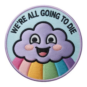 Può includere: Toppa ricamata rotonda con una nuvola viola sorridente e un arcobaleno. Il testo "WE'RE ALL GOING TO DIE" è in nero. La toppa ha un bordo azzurro.