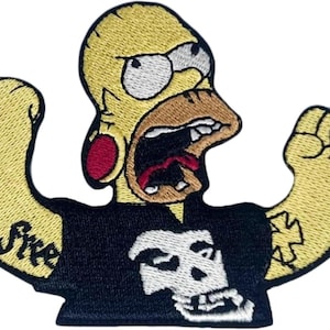 Peut inclure: Un écusson brodé représentant un personnage de dessin animé jaune avec une tête chauve, de grands yeux et une bouche ouverte. Le personnage porte un t-shirt noir avec un motif de crâne blanc, un écarteur d'oreille rouge et des tatouages.