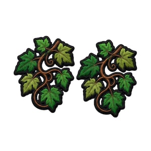 May include: Two identical embroidered patches featuring a brown winding vine with multiple green maple-shaped leaves. Each patch has a thick black border outlining the organic shape of the foliage and stems, creating a distinct contrast.