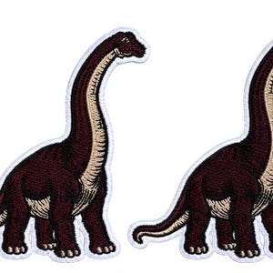 May include: Two identical embroidered patches featuring a long-necked dinosaur, specifically a sauropod, with dark brown skin and a light beige underbelly. Each patch has a white stitched border outlining the shape of the dinosaur figure.