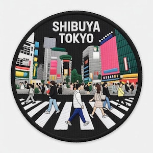 Puede incluir: Un parche bordado circular que presenta una escena detallada del cruce de Shibuya en Tokio. El diseño incluye edificios estilizados, una multitud de personas cruzando un paso de peatones blanco y el texto SHIBUYA TOKYO en letras blancas.