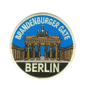 Könnte beinhalten: Runder Aufnäher mit blauem Hintergrund und den Worten "BRANDENBURGER GATE" in Weiß. Der Aufnäher zeigt das Brandenburger Tor in Berlin, Deutschland, mit dem Wort "BERLIN" in Weiß am unteren Rand.