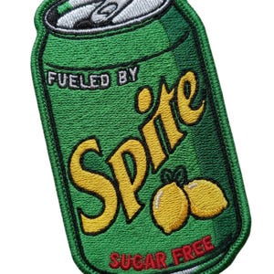 Può includere: Toppa ricamata a forma di lattina verde con la scritta "Fueled By Sprite" in giallo e "Sugar Free" in rosso. Presenta due limoni gialli. La parte superiore della lattina è argentata.