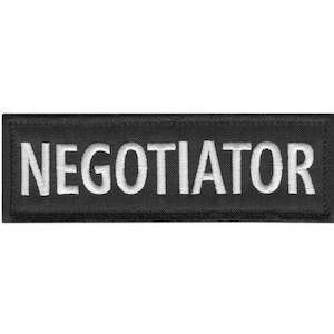 May include: A white ceramic mug with a black handle and the text "But First, Coffee" in a bold, black font. The mug is filled with a dark liquid, likely coffee, and rests on a light-coloured surface.