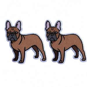 Puede incluir: Dos parches bordados idénticos, cada uno con un bulldog francés marrón con hocico negro, orejas erguidas y un borde blanco. Los perros se muestran de perfil, de pie, con costuras detalladas y una silueta canina claramente definida.