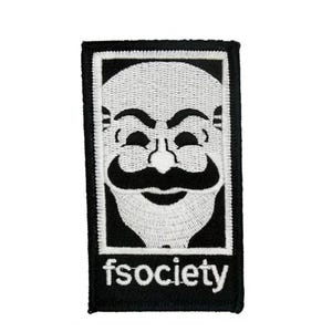 Può includere: Una toppa rettangolare ricamata con un design in bianco e nero di una maschera stilizzata con baffi e barba. La parola fsociety è ricamata in lettere minuscole bianche nella parte inferiore della toppa su uno sfondo nero.