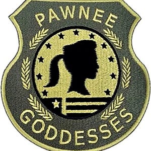 以下が含まれることがあります： オリーブグリーンと淡い黄色の盾型刺繍ワッペン。PAWNEE GODDESSESの文字が黄色で刺繍されています。中央の円には、星と麦の穂に囲まれた、横顔の人物の黒いシルエットが描かれています。
