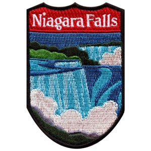 Puede incluir: Un parche bordado en forma de escudo con un paisaje de las cataratas del Niágara. La banda roja superior muestra el texto blanco Niagara Falls. Debajo, hilos azules y celestes representan agua en cascada, niebla blanca y follaje verde.