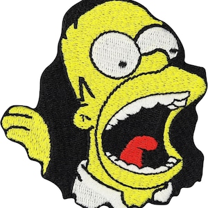 May include: An embroidered patch featuring a yellow cartoon character with a wide-open mouth, white eyes, and a red tongue. The character is set against a black background, with a white collar visible at the bottom and a yellow hand extended to the left.