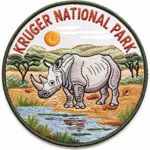 Può includere: Toppa ricamata raffigurante un rinoceronte in un paesaggio della savana con la scritta "KRUGER NATIONAL PARK". La toppa ha una forma circolare con un bordo verde, un sole giallo e uno specchio d'acqua.