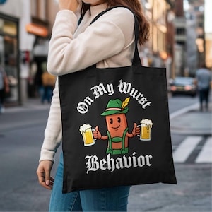 May include: A black tote bag featuring a cartoon sausage character wearing a green hat with a feather and green lederhosen. The character holds two mugs of beer. The text "On My Wurst Behavior" is printed in white above and below the graphic.