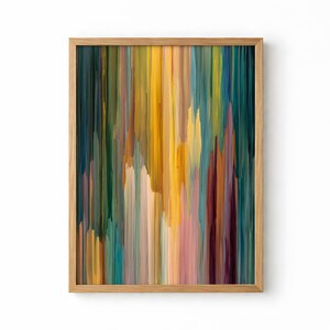 May include: Abstract art print in a wooden frame. The artwork features vertical brushstrokes in shades of yellow, teal, green, pink, and brown. The colors blend together to create a textured, painterly effect. The frame is a light-colored wood.