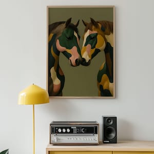 May include: A framed art print featuring two horses with abstract camouflage-style patterns in green, pink, yellow, and brown. The artwork is displayed on a wall above a stereo system and a yellow floor lamp.
