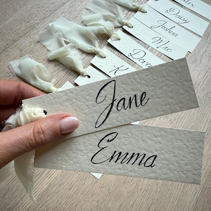 Elegant, handcrafted wedding table name cards in modern calligraphy – the perfect finishing touch for your special day with a custom ribbon