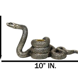 K&ouml;nnte beinhalten: Ein silberfarbener, schlangenf&ouml;rmiger Kerzenhalter. Der gewundene K&ouml;rper der Schlange bildet die Basis, mit erhobenem Kopf. Der Kerzenhalter ist 25,4 cm lang und 10,8 cm hoch.