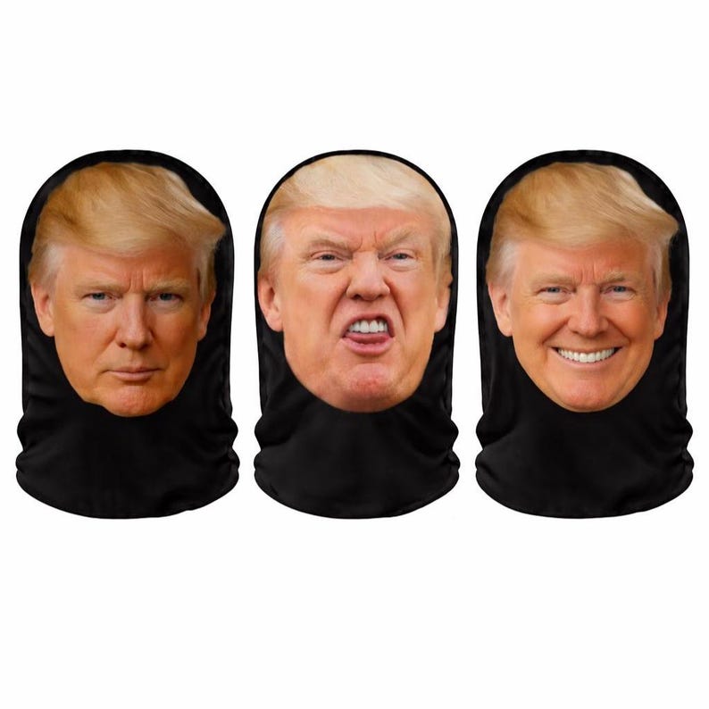 May include: Three black face coverings each featuring a different facial expression of a man with blonde hair. The expressions include a neutral face, an angry face, and a smiling face.