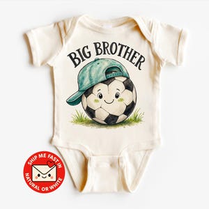 Könnte beinhalten: Ein cremefarbener Babybody mit einer Grafik eines lächelnden Fußballs, der eine türkisfarbene Baseballkappe trägt, und dem Text BIG BROTHER darüber. Der Fußball ist auf einem kleinen Stück grünem Gras abgebildet.