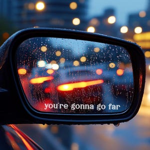 Könnte beinhalten: Nasser Autospiegel mit Regentropfen, der verschwommene Ampeln und den Text "you're gonna go far" reflektiert. Der Hintergrund zeigt Bokeh-Lichter. Der Spiegel ist schwarz.