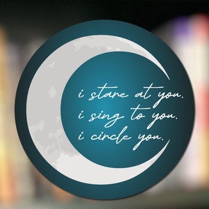 May include: A round teal graphic with a white crescent moon design. The text "i stare at you. i sing to you. i circle you." is written in white script. The background is blurred.