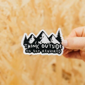 May include: White sticker with a black mountain range design and the text "Think Outside No Box Required".
