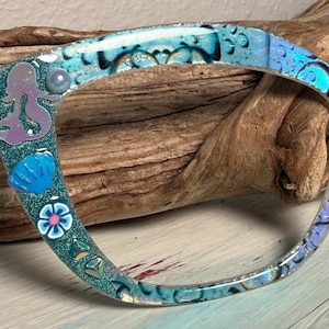 May include: A white ceramic mug with a black handle and the text "But First, Coffee" in a bold, black font. The mug is set against a neutral background, highlighting its simple design.