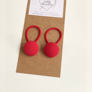 May include: Two red fabric-covered button earrings with elastic loops. The earrings are attached to a brown card with the text "little thimbles" and Etsy and Instagram account information.