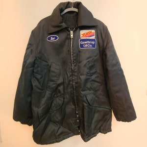 May include: Black quilted jacket with a zipper closure and two pockets. The jacket has two patches, one that says "Bob" and another that says "York Manufacturing Company Gawthrop Oil Co."
