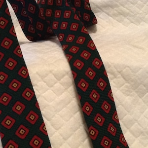 May include: A green tie with a red and gold diamond pattern.
